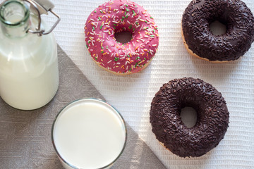 Doughnuts on a white tablecloth with a glass of milk. View from above.