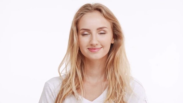 Young beautiful Caucasian blonde girl flirting at camera ogling raising eyebrows on white background