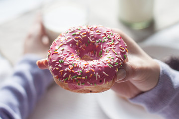 Girl in a lilac blouse holding a pink donut