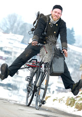 Schornsteinfeger fährt Fahrrad in Arbeitskleidung durch Winterlandschaft