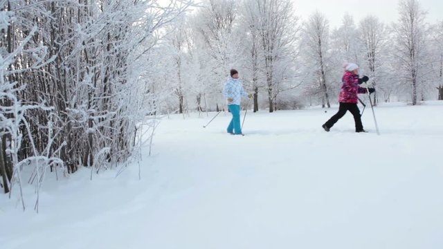 Russian people, an adult woman and child skiing in urban park at winter season. Russia
