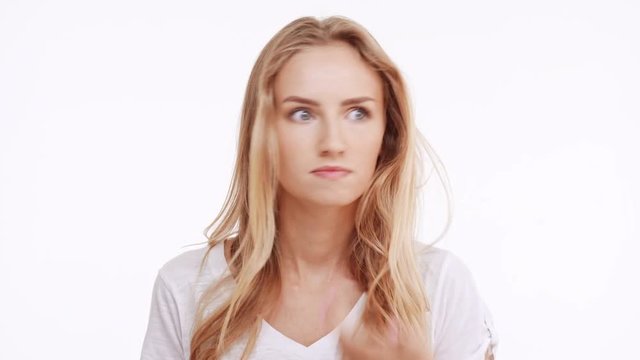 Young beautiful Caucasian blonde girl actively diasagrees wonders puzzles on white background