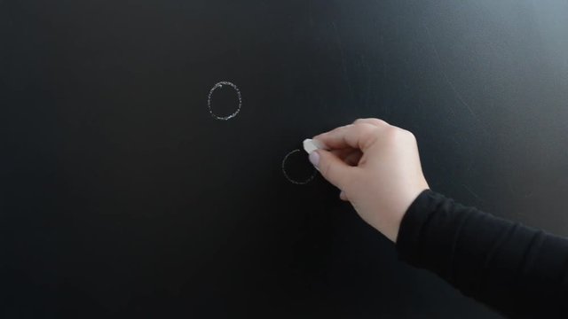 We draw chalk camomile flowers on a board.
