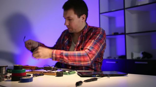 The wizard verifies the solder on the circuit board with a magnifying glass with diode illumination.