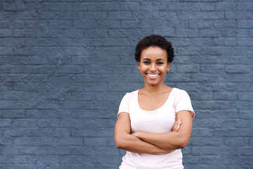 smiling black woman standing against gray wall