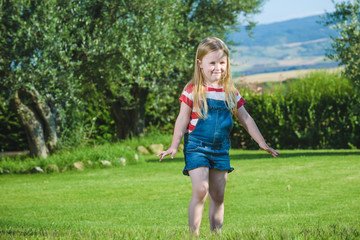Summer play small beautiful blond girl on green grass