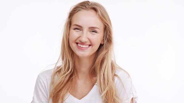 Young beautiful Caucasian blonde girl smiling laughing on white background