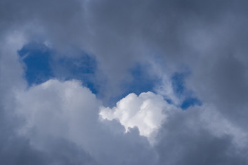 Bright blue sky and white cloud peek out from clearance in dark