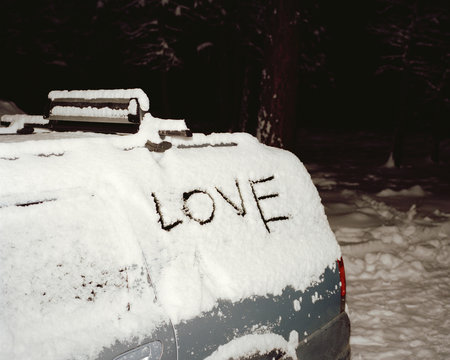 Love written on window of snow covered car 