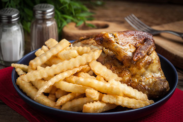 Roasted chicken with french fries on a plate.