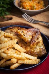 Roasted chicken with french fries on a plate.
