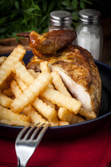 Roasted chicken with french fries on a plate.