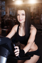 Obraz na płótnie Canvas Muscular young woman wearing sportswear training on exercise bikes in gym. Intense cardio workout.