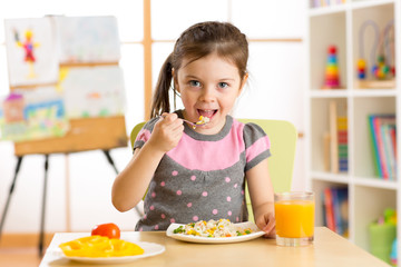 kid girl eating healthy food at home