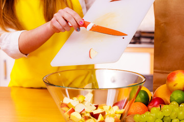 Woman housewife in kitchen cutting apple fruits