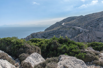 winding road on mountainside at the coast with blue sky and ocean far below