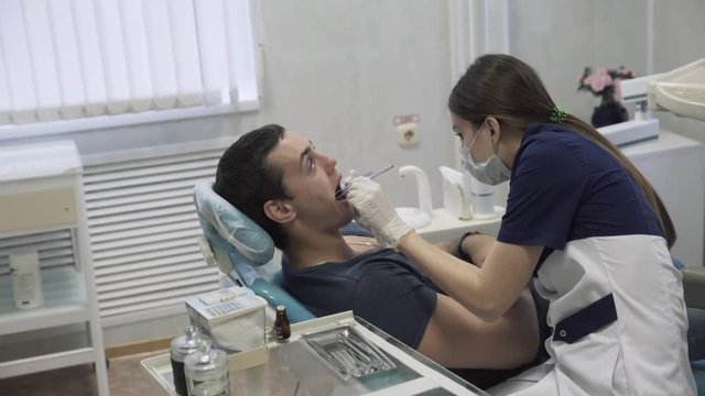 Dentist young woman making procedures to men patient at dental office. Concept of healthy life