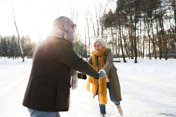 Senior couple in sunny winter nature ice skating.