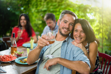 portrait of a couple, they sit with friends around a table