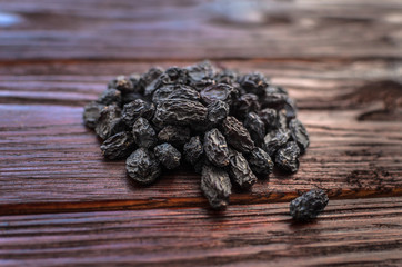 Dark dried grapes (raisins) on a texture wooden table