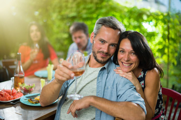 portrait of a couple, they sit with friends around a table