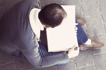 Handsome young man reading book outdoors (close up)