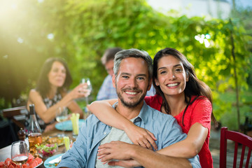 portrait of a couple, they sit with friends around a table