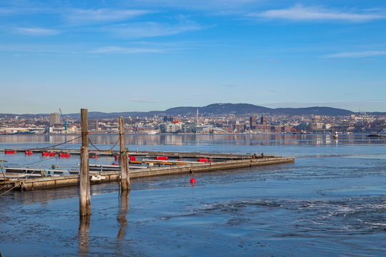 Old wooden pier on the island with Oslo waterfront at the backgound