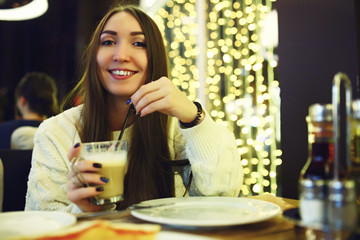 Beautiful young woman drinking coffee at cafe. Tonned. Selective focus.