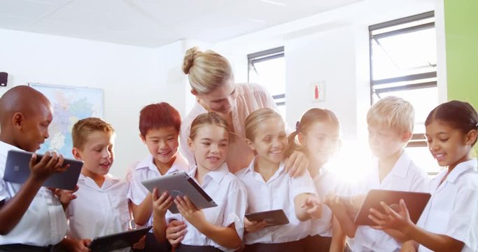 Teacher teaching kids on digital tablet in classroom at school 4k