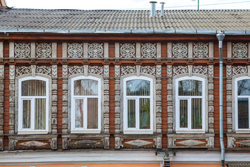 Wall of wooden traditional russian house with windows and carved frames and pattern