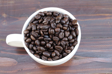 Coffee cup and coffee beans on wooden background. Top view.