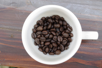 Coffee cup and coffee beans on wooden background. Top view.