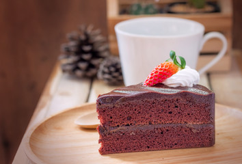 Slice of chocolate cake with strawberries in wood plate on a wooden table.