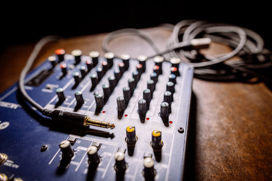 Close up shot of a mixer desk with many buttons and cables.