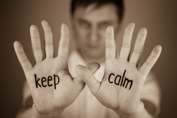 man showing  the word "Keep calm" written on the palm of a his hand