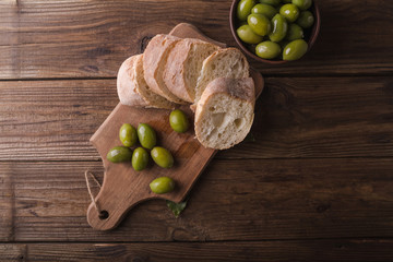 Green olives on a wooden board ciabatta on wooden background. Ciabatta. Sliced ciabatta