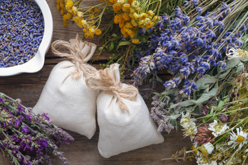Bunch of healing herbs and sachet on wooden table. Top view.