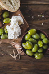 Green olives, sliced ciabatta, feta cheese on a wooden board. Spice. Garlic. Chees Feta. Ciabatta. Olives on a wooden background. Copyspace