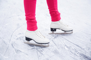 Woman skating and training with white skates on the ice area in winter day. Weekends activities...