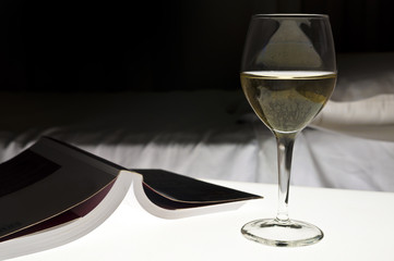 Book, white wine, bed. Evening relax concept