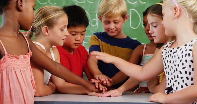 School kids stacking hands in classroom at school 4k