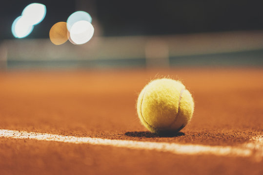 Tennis ball on empty court at night, blurred background, area with copy space for your text message or design