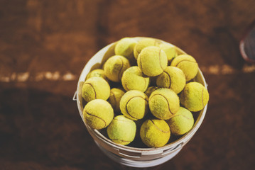 Yellow tennis balls at hopper on a court, sportive and healthy lifestyle