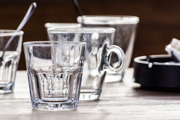 Close-up picture of a glass  water which is half-full standing on  brown wooden table and as the sun shines through the  the reflection can be seen  the 