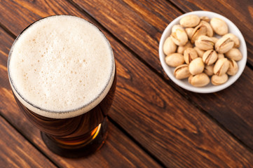 glass of dark cold frothy beer, nuts old wooden table