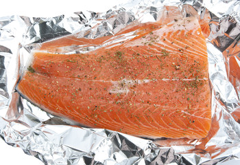 Raw salmon with herbs in aluminum foil waiting for cooking