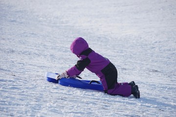 Fototapeta na wymiar Mädchen im Skioverall beim Rodeln