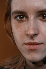 Portrait of a beautiful girl with freckles in studio on a brown background
