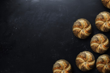 Crusty fresh kaiser rolls on black background.